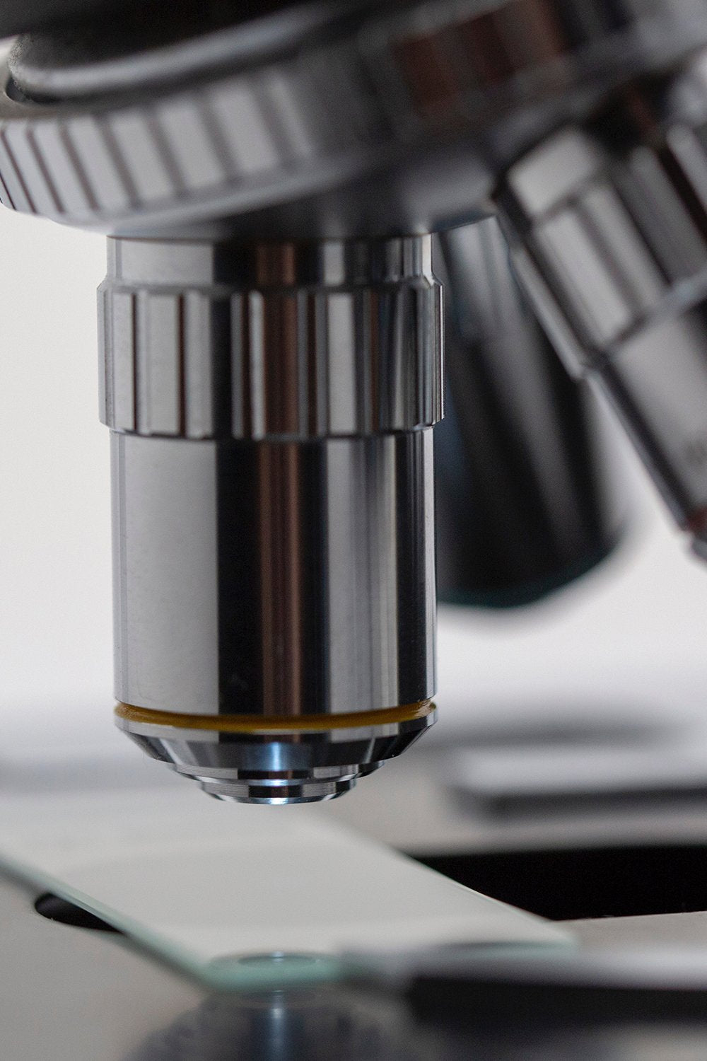 Close-up of a laboratory microscope's lens and stage with a slide, used to illustrate lab testing.